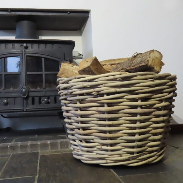 Ronde houtmand van rotan bij de openhaard